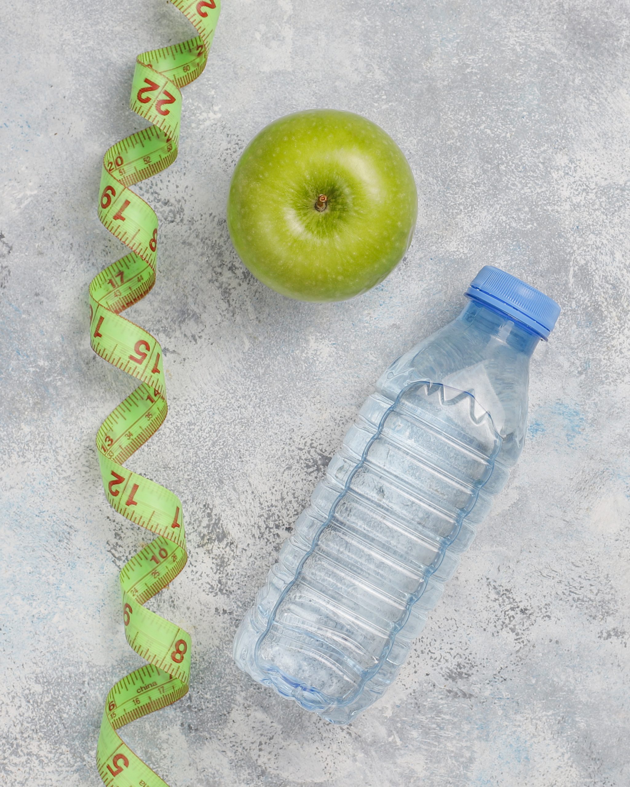 ENVALPRI SA 1 manzana verde fresca cinta metrica botella agua dulce sobre hormigon gris scaled
